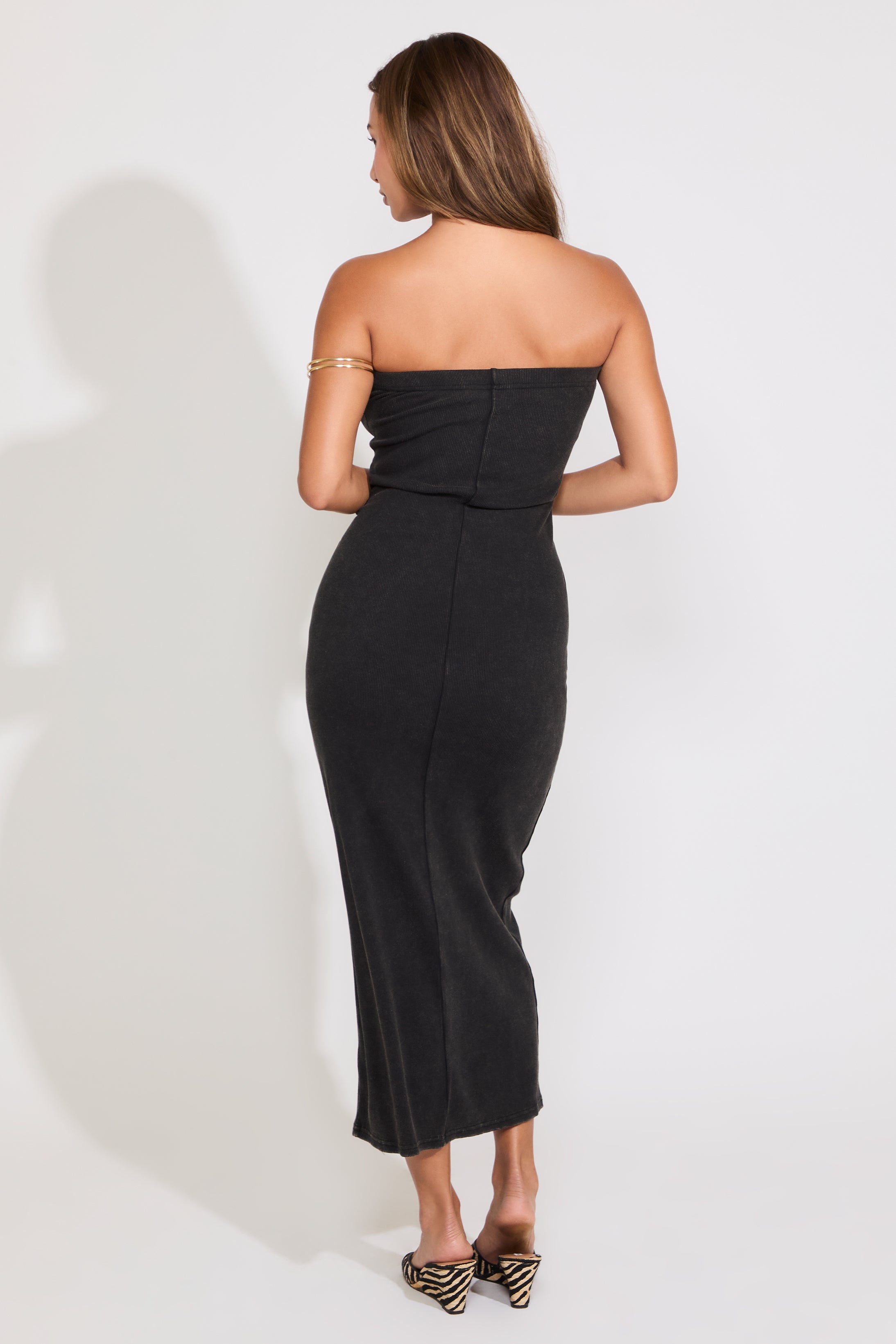 Model is wearing a black acid washed ribbed midi tube dress on a white background.