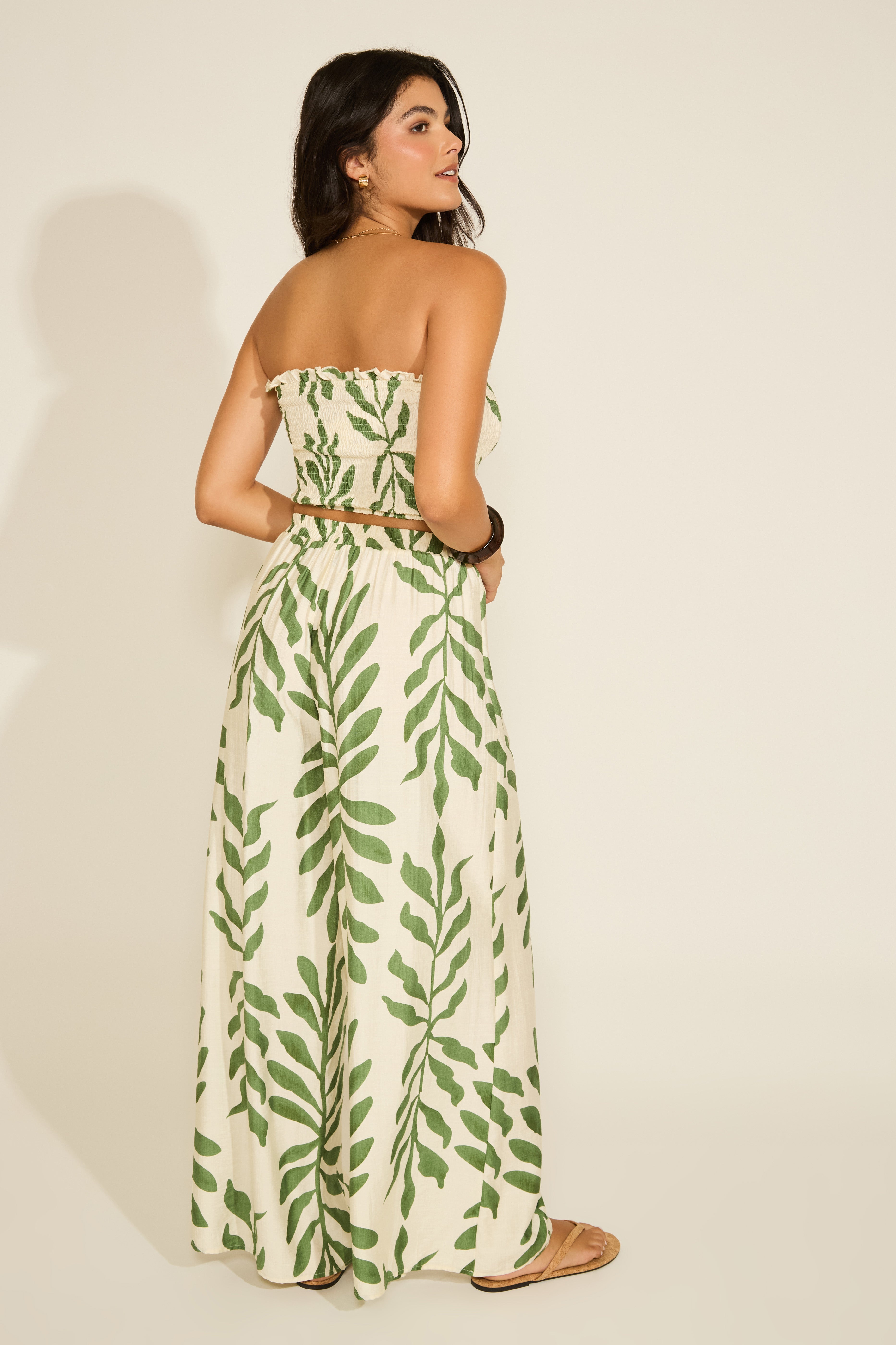 Woman wearing a strapless dress with green leaf pattern on a plain background