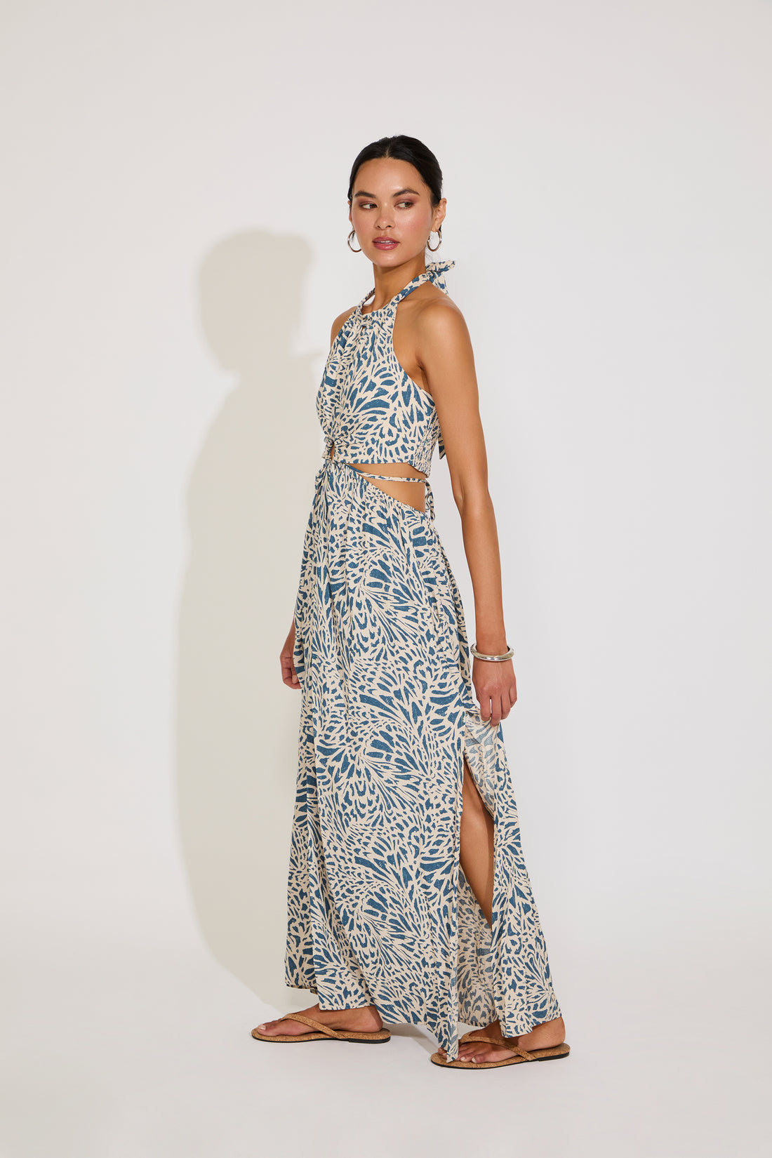 Woman wearing a floral halter neck dress with a slit on a white background