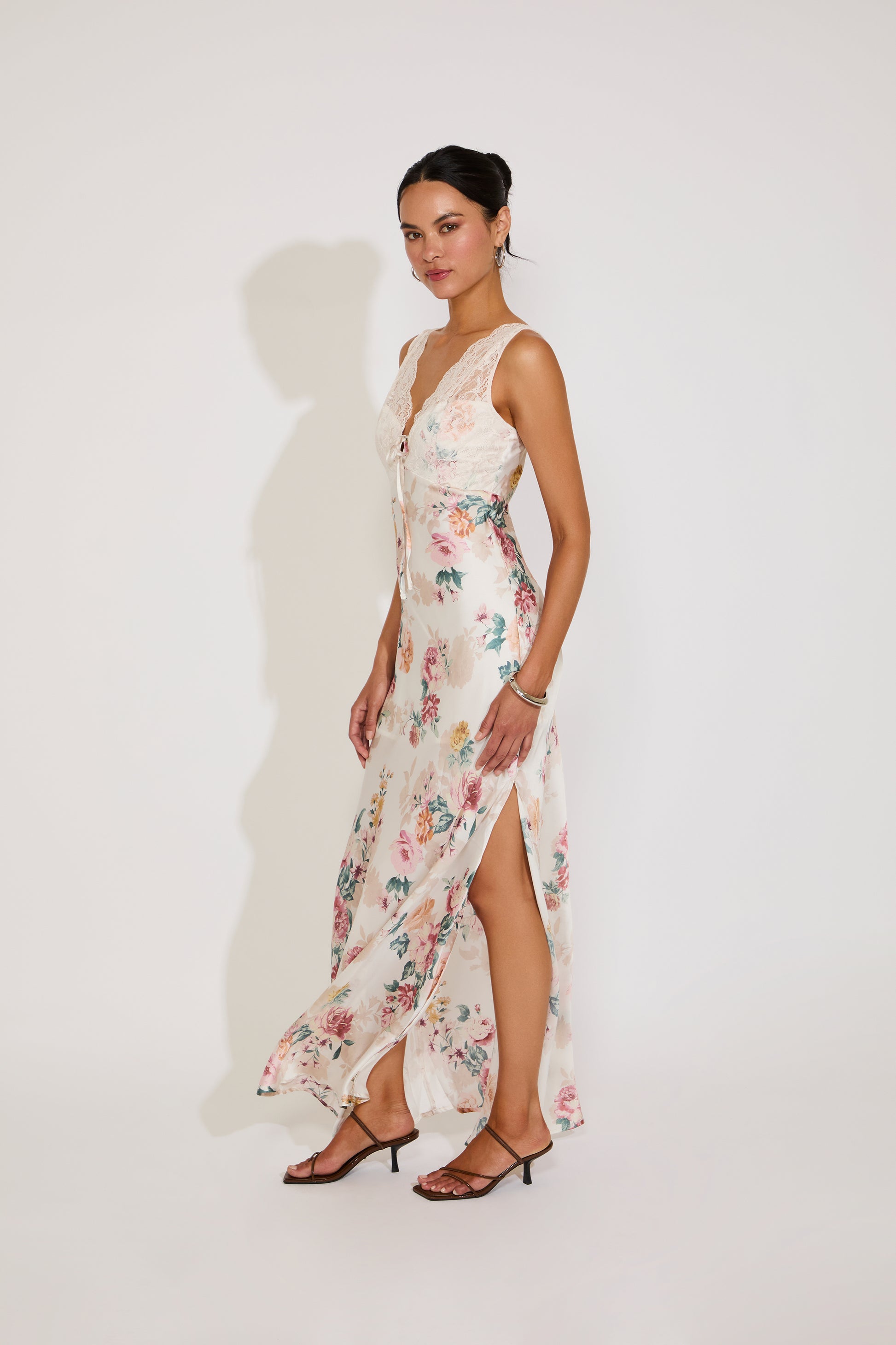 Woman wearing a floral dress with a slit on a white background