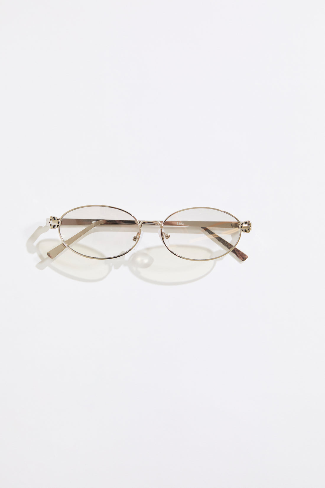 Gold rimmed glasses with olive lenses on a  white background