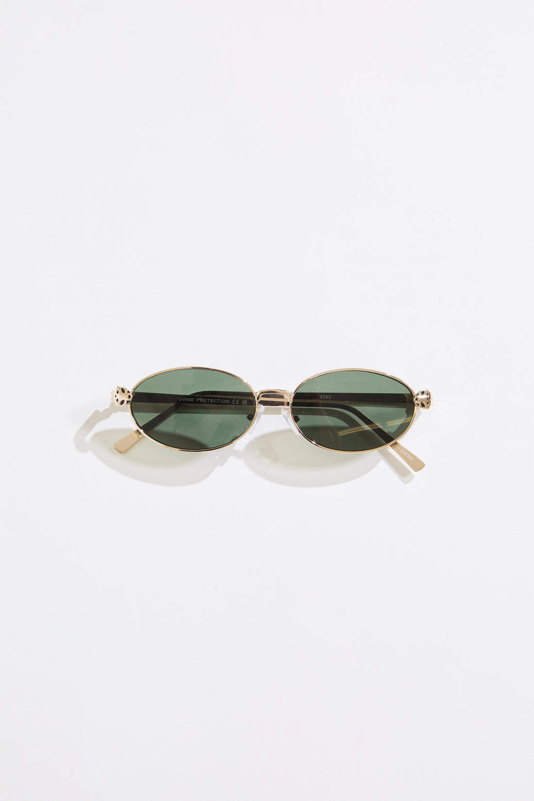 Gold rimmed glasses with olive lenses on a  white background