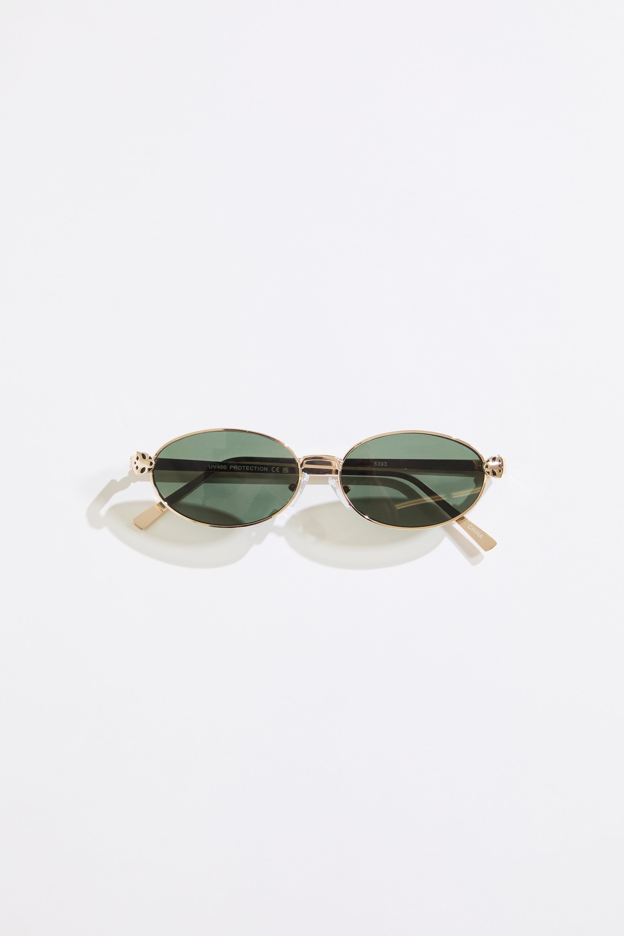 Gold rimmed glasses with olive lenses on a  white background