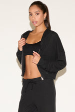 Woman wearing a black athletic outfit on a plain background