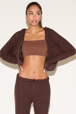 Woman wearing a brown athletic outfit on a white background