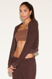 Woman wearing a brown athletic outfit on a plain background