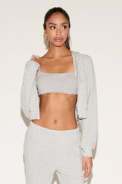 Woman wearing a light gray athletic outfit on a white background