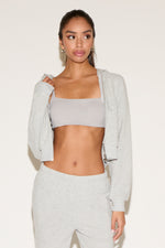 Woman wearing a light gray athletic outfit on a white background