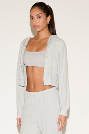 Woman wearing a light gray cropped hoodie and pants on a white background