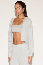 Woman wearing a light gray cropped hoodie and pants on a white background
