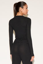 Woman wearing a black bodysuit against a white background
