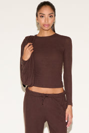 Woman wearing a brown long-sleeve top and pants on a white background