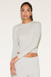 Woman wearing a gray long-sleeve top and skirt set on a white background