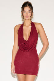 Woman wearing a burgundy halter neck dress on a white background