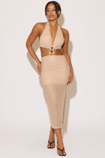 Woman wearing a beige halter neck dress with a belt on a white background
