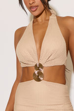 Beige woven halter top with gold circular accents on a plain background