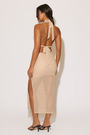 Woman wearing a beige halter neck dress with mesh panels on a white background