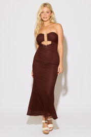 Woman wearing a strapless brown evening gown with a cutout design on a white background.