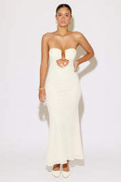 Woman wearing a strapless white evening gown with a cutout design on a white background