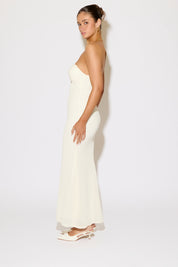 Woman wearing a strapless white gown against a plain background