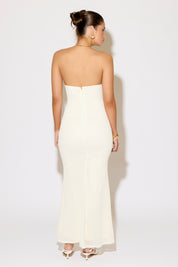 Woman wearing a strapless white dress against a plain background