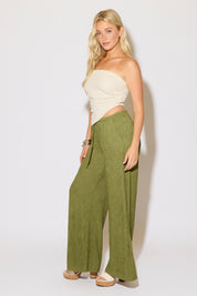 Model is wearing a striped strapless pointed hem bandana top with green flowy pants on a white background.