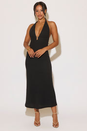 Woman wearing a black halter neck dress against a white background