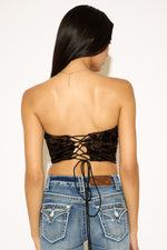 Person wearing a black lace-up top and blue jeans on a white background