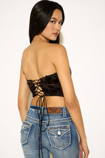 Woman wearing a black lace-up top and blue jeans on a white background