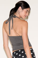 Woman wearing a gray halter top with tied straps on a white background