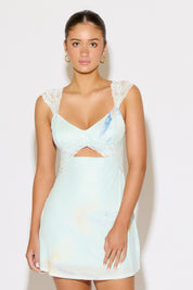 Woman wearing a light blue dress with lace details on a white background
