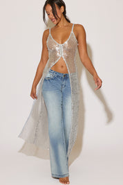 Woman wearing a sparkly silver top and blue jeans on a white background