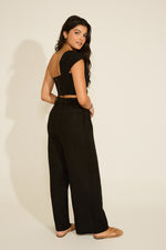 A woman wearing a black linen two-piece set with a front twist detail top and wide-leg pants.
