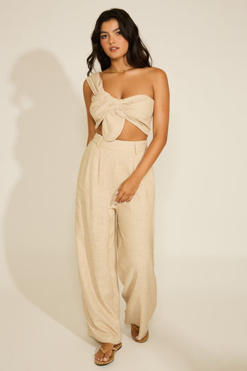 A woman wearing a beige linen two-piece set with a front twist detail top and wide-leg pants.