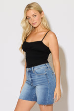 Model is wearing a black ruched bust strappy cami top with denim shorts on a white background. 