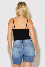 Model is wearing a black ruched bust strappy cami top with denim shorts on a white background. 