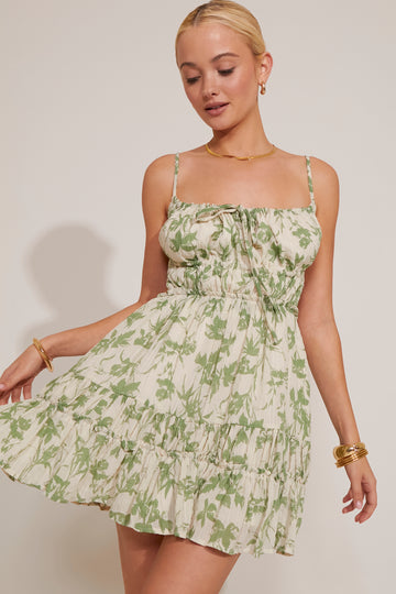 Woman wearing a green floral dress against a plain background