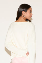 Woman wearing a white sweater against a plain background