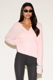 Woman wearing a light pink blouse and black polka dot pants on a white background