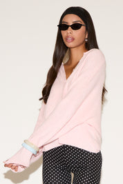 Woman wearing a light pink sweater and polka dot pants on a white background