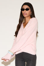 Woman wearing a light pink sweater and polka dot pants on a white background