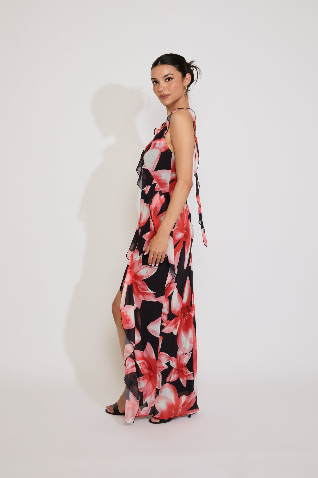 Woman wearing a floral dress with a slit on a white background