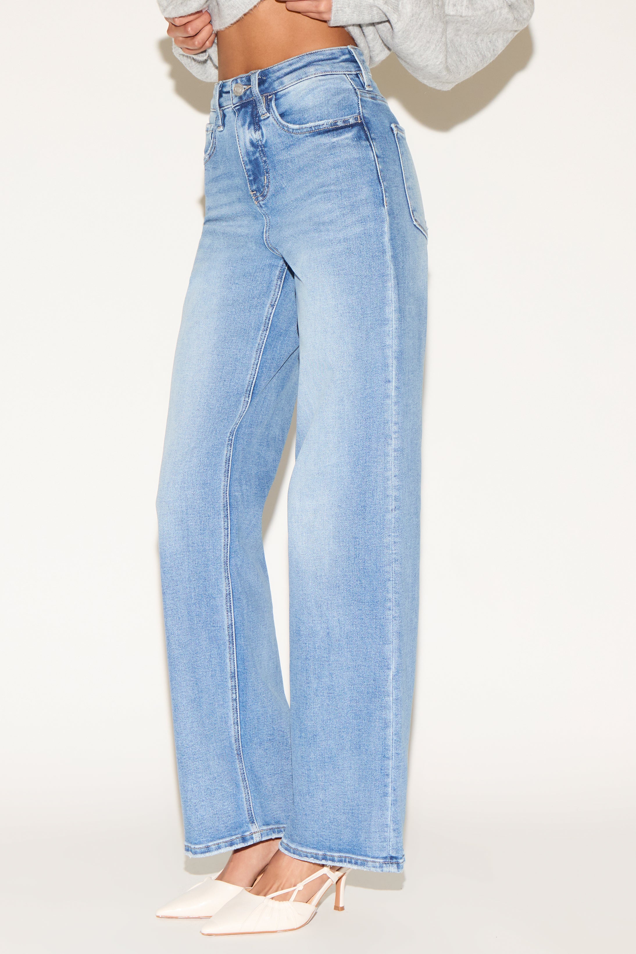 Side view of model wearing light wash denim jeans.