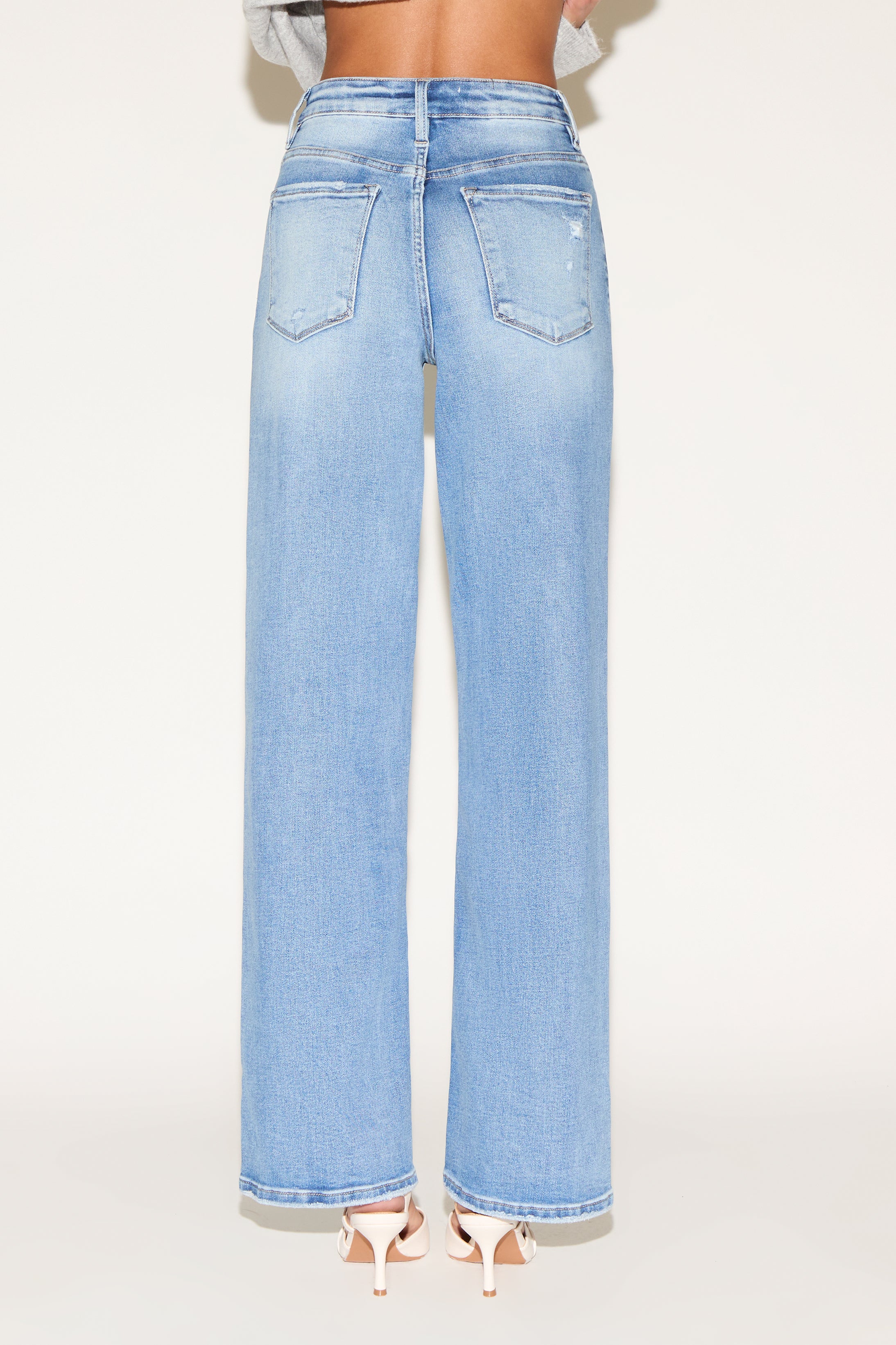 Back view of model wearing light wash denim jeans.