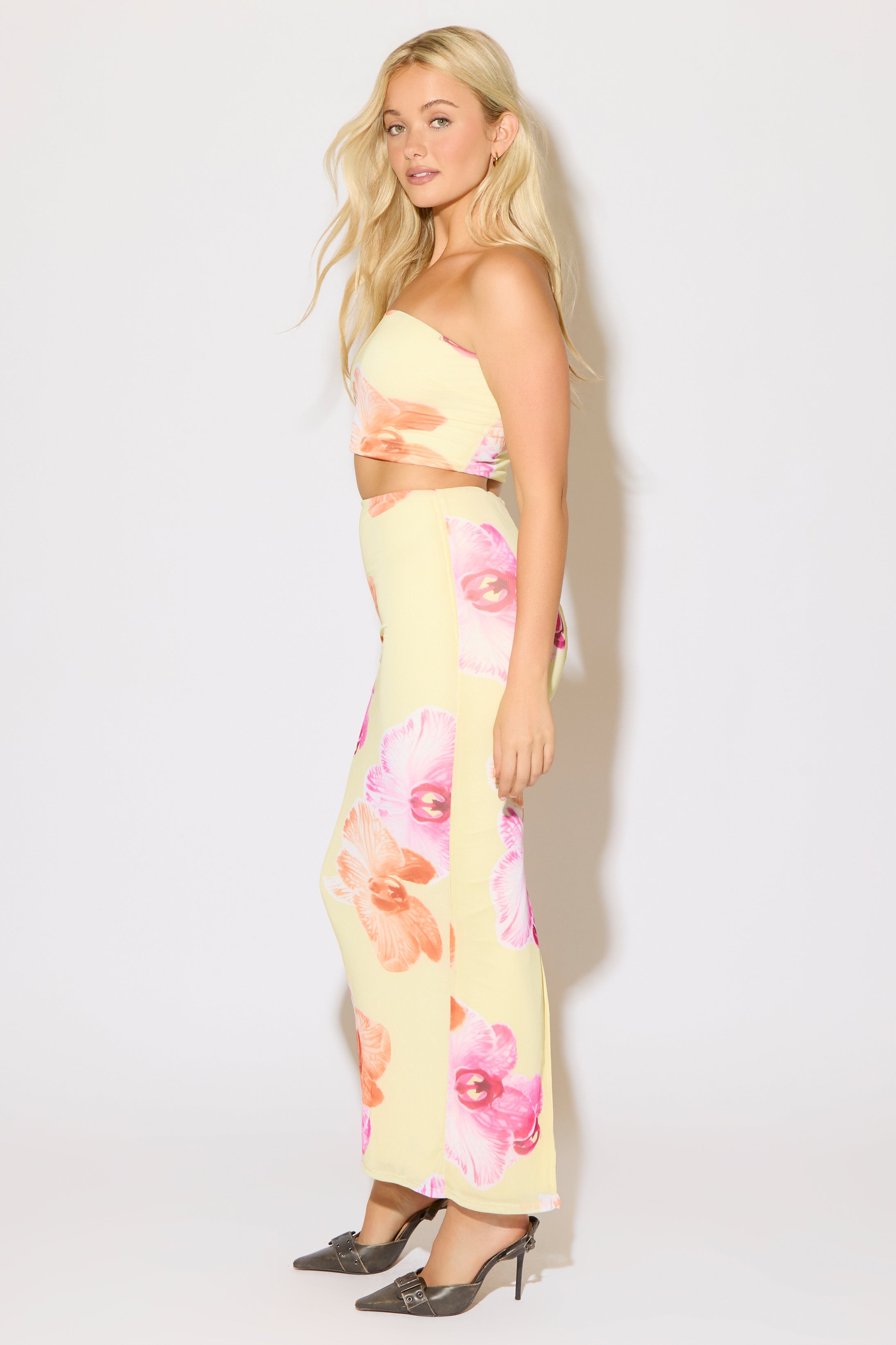 Model is wearing a yellow floral print crop tube top and maxi skirt set on a white background.