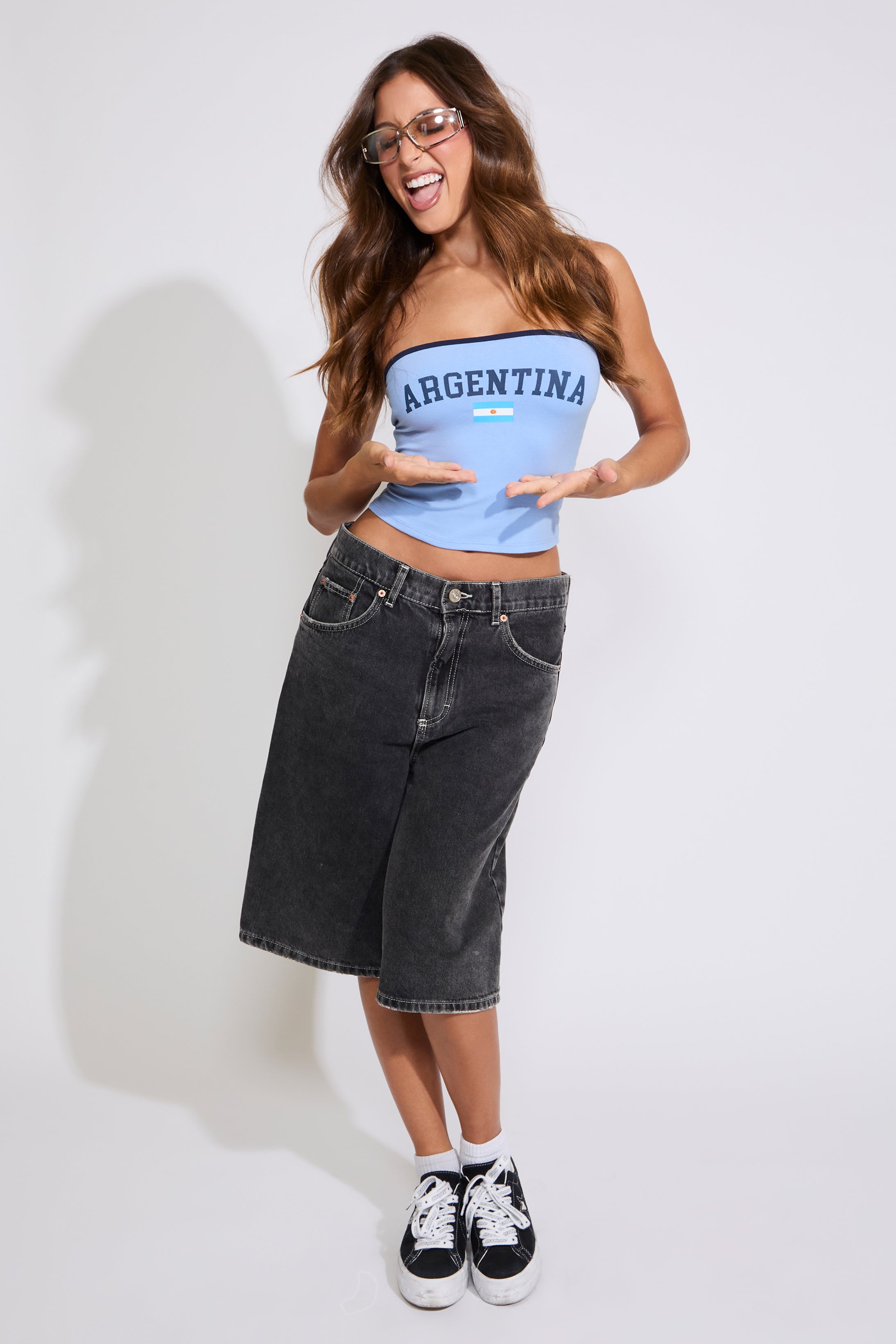 Model is wearing a blue Argentina strapless tube top with washed black denim jorts on a white background.