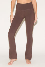 A person wearing brown yoga pants on a light background.