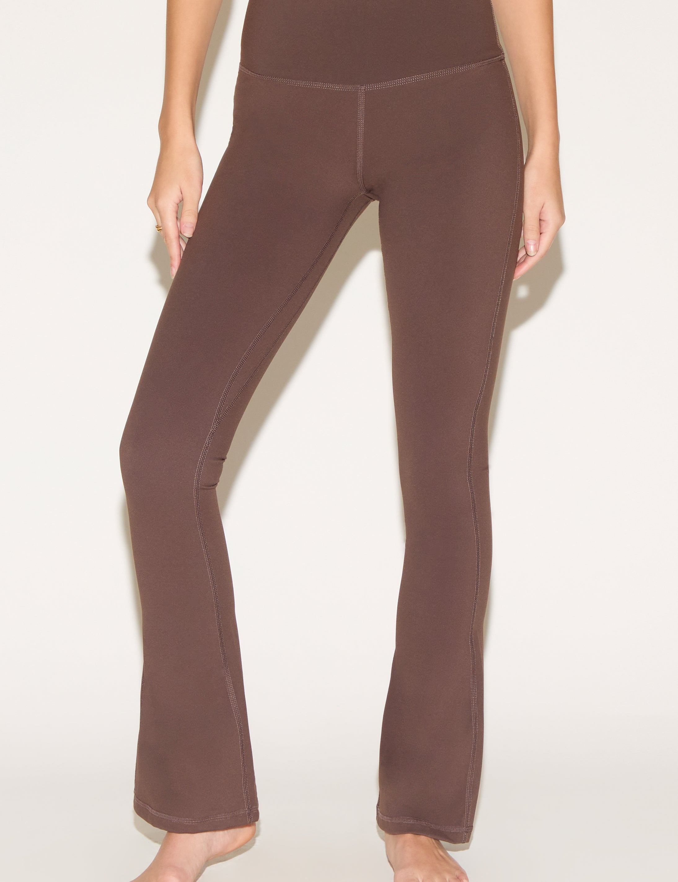 A person wearing brown yoga pants on a light background.