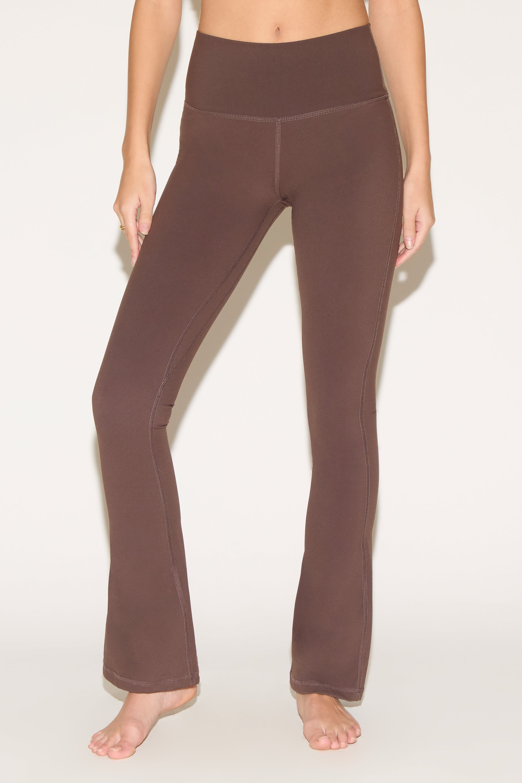 A person wearing brown yoga pants on a light background.