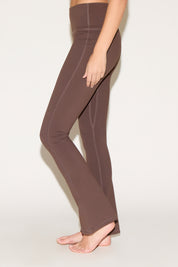 A person wearing brown yoga pants on a light background.